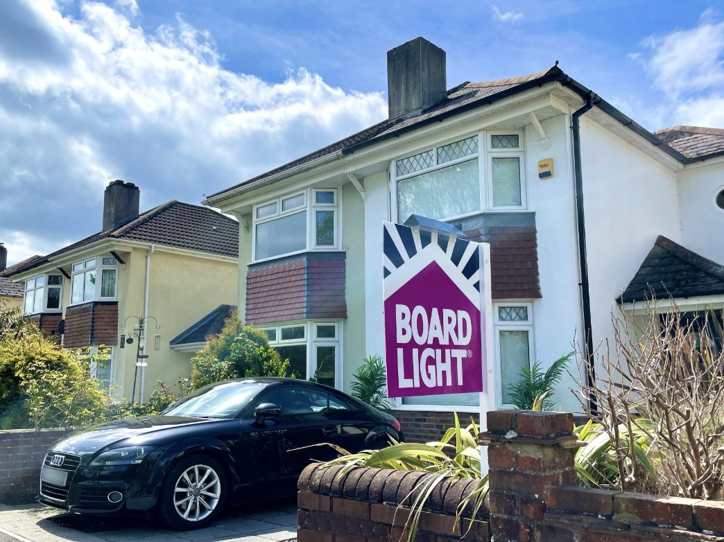 House with a 'Boardlight' sign in front, car parked on the street