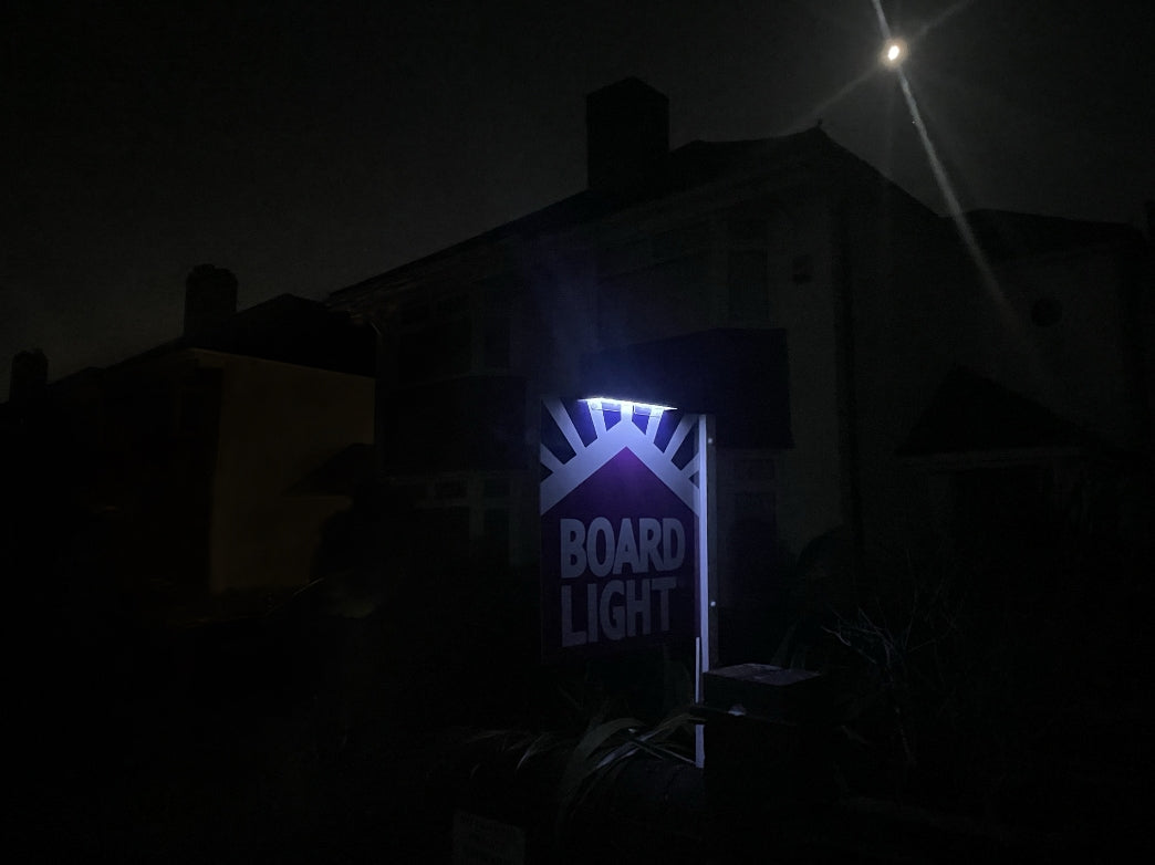 Boardlight device glowing in the dark with a building in the background